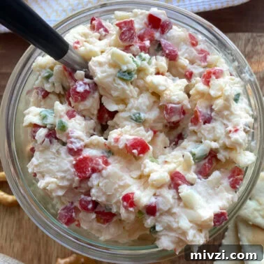 Spicy Jalapeño Pimento Cheese Dip Recipe 10 A bowl of creamy jalapeño pimento cheese made with white cheddar cheese with a spoon.