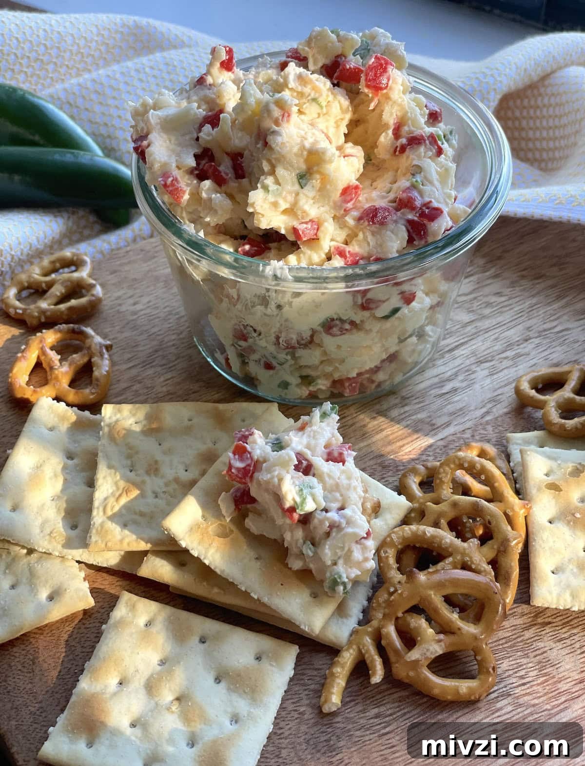 Spicy Jalapeño Pimento Cheese Dip Recipe 11 A jar of pimento cheese with jalapeños surrounded by saltines and pretzels.