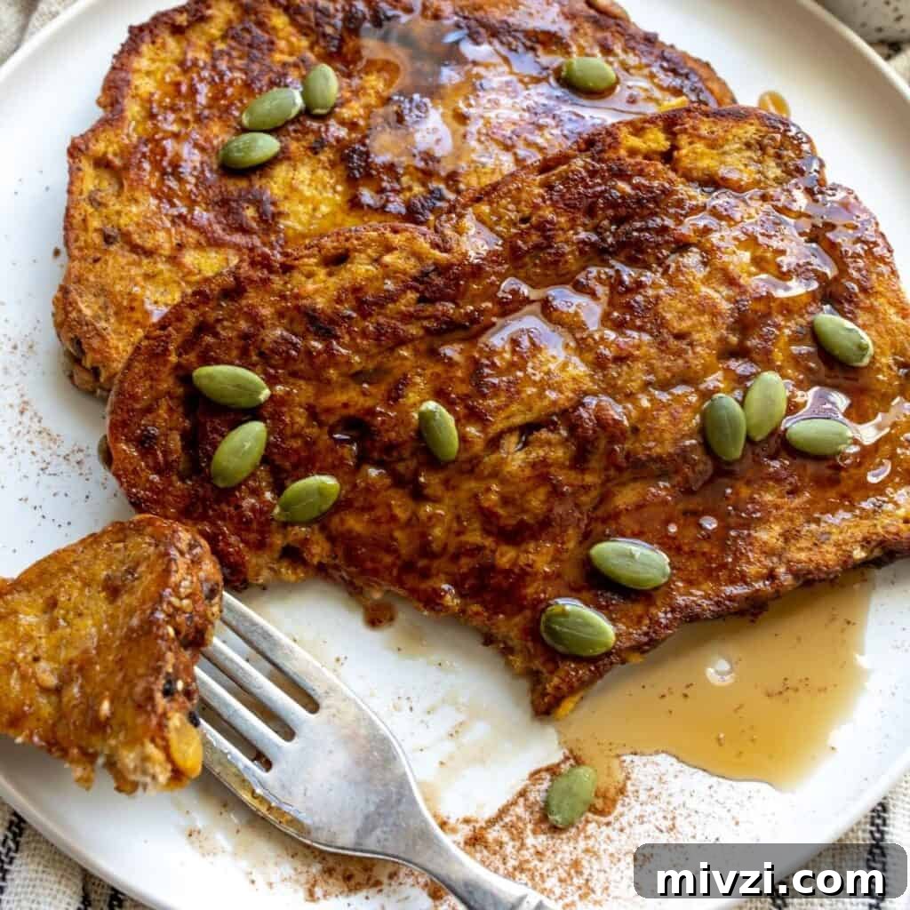 Pumpkin Spice French Toast on a white plate with syrup with a bite cut and on a fork.