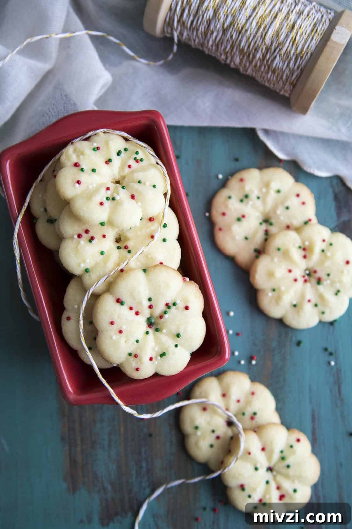 Crisp Almond Spritz Cookies Recipe for Holiday Baking 2 Almond Spritz Cookies in a red ceramic container.