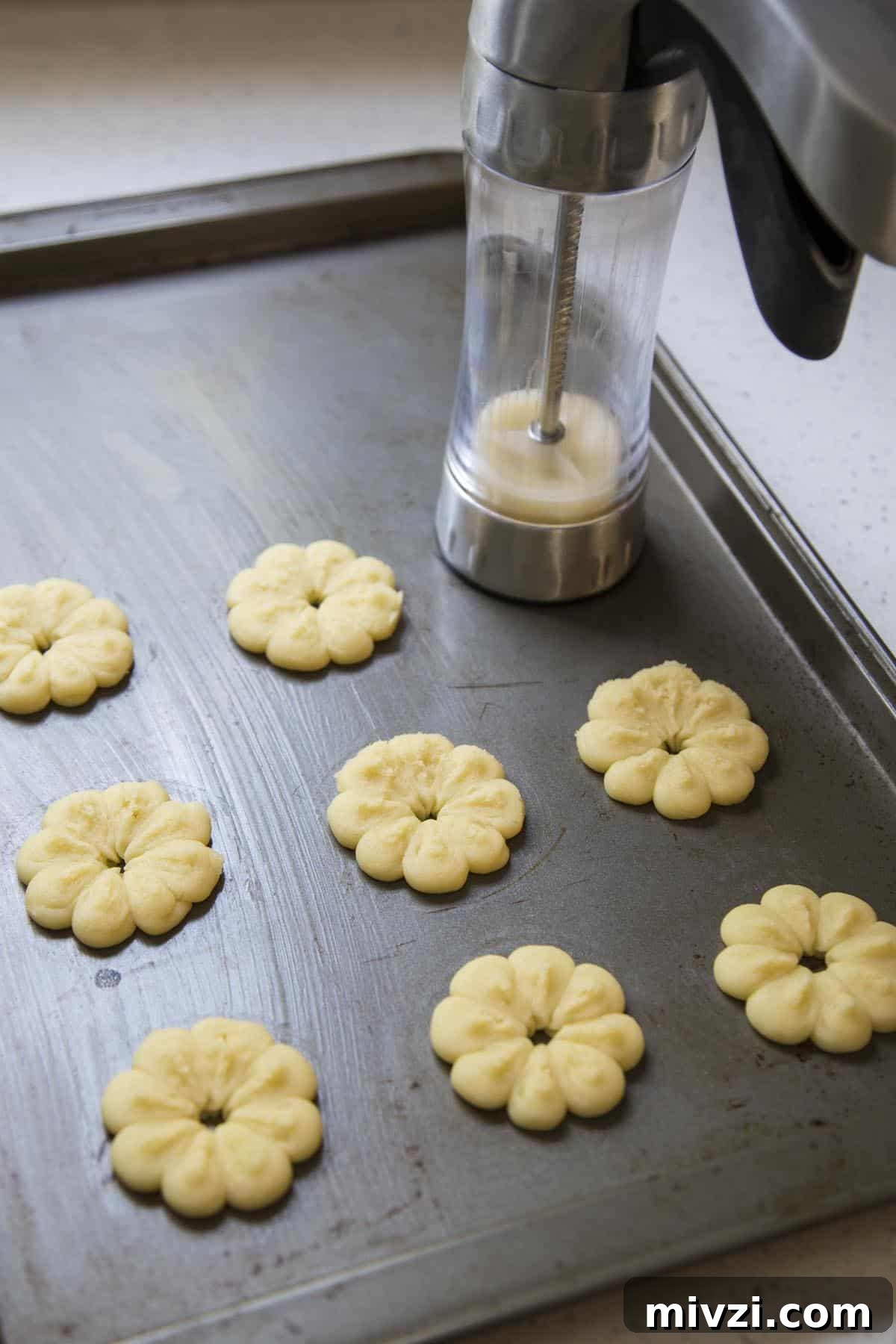 Crisp Almond Spritz Cookies Recipe for Holiday Baking 6 Forming Almond Spritz Cookies with a cookie press.