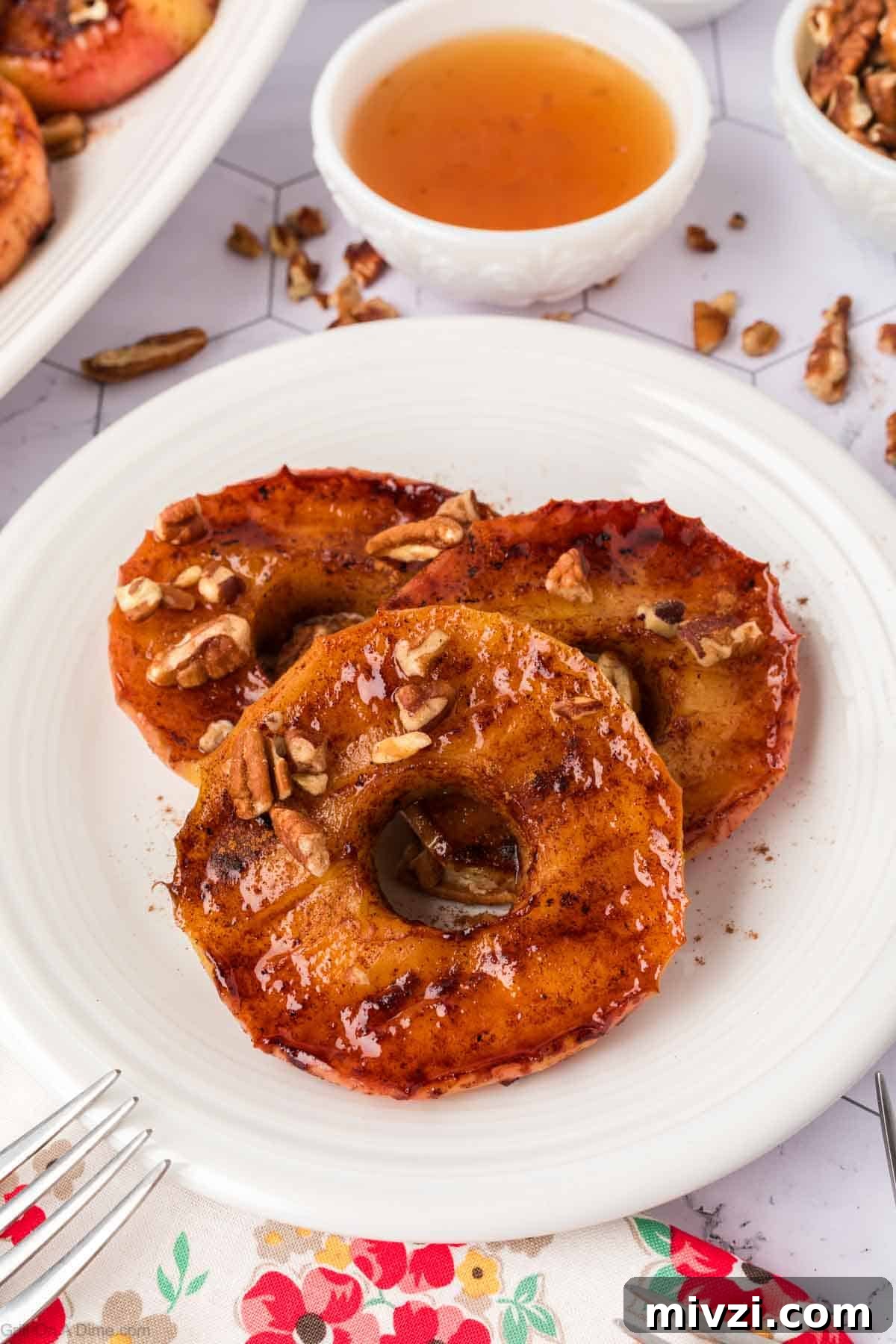 Caramelized Grilled Apples with Cinnamon and Honey 12 slice caramelized apples topped with chopped pecans on a plate