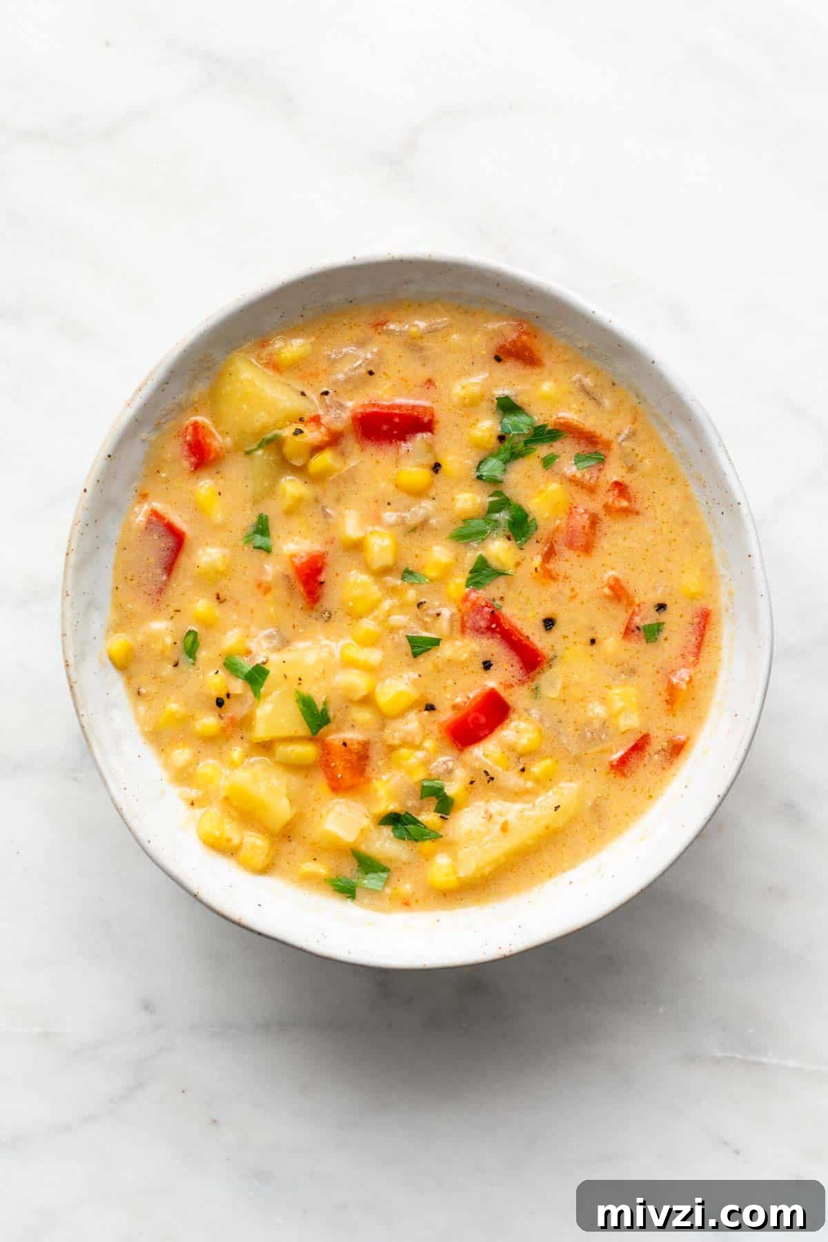 Vegan potato and corn chowder in a bowl garnished with parsley.