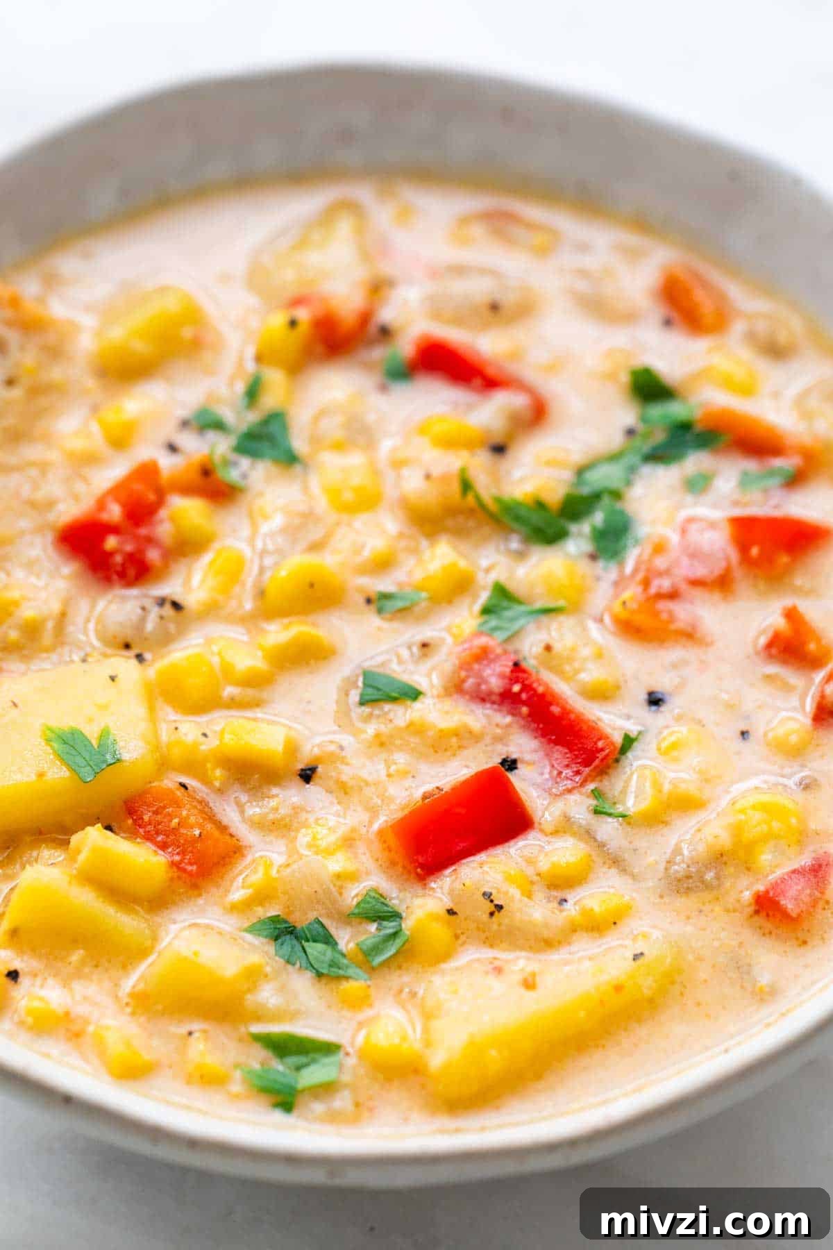 Bowl of vegan potato and corn chowder topped with fresh parsley.