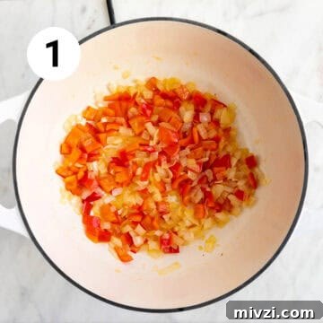 Garlic and red bell pepper sautéed in a large pot.