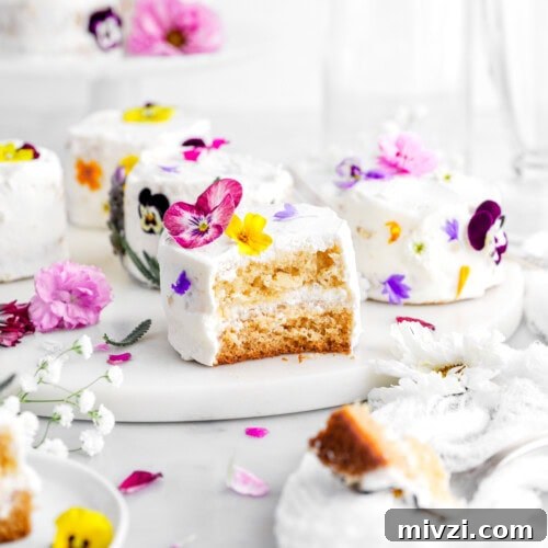 bite missing from mini honey orange blossom cake on marble tray with more mini cakes behind and edible flwoers.