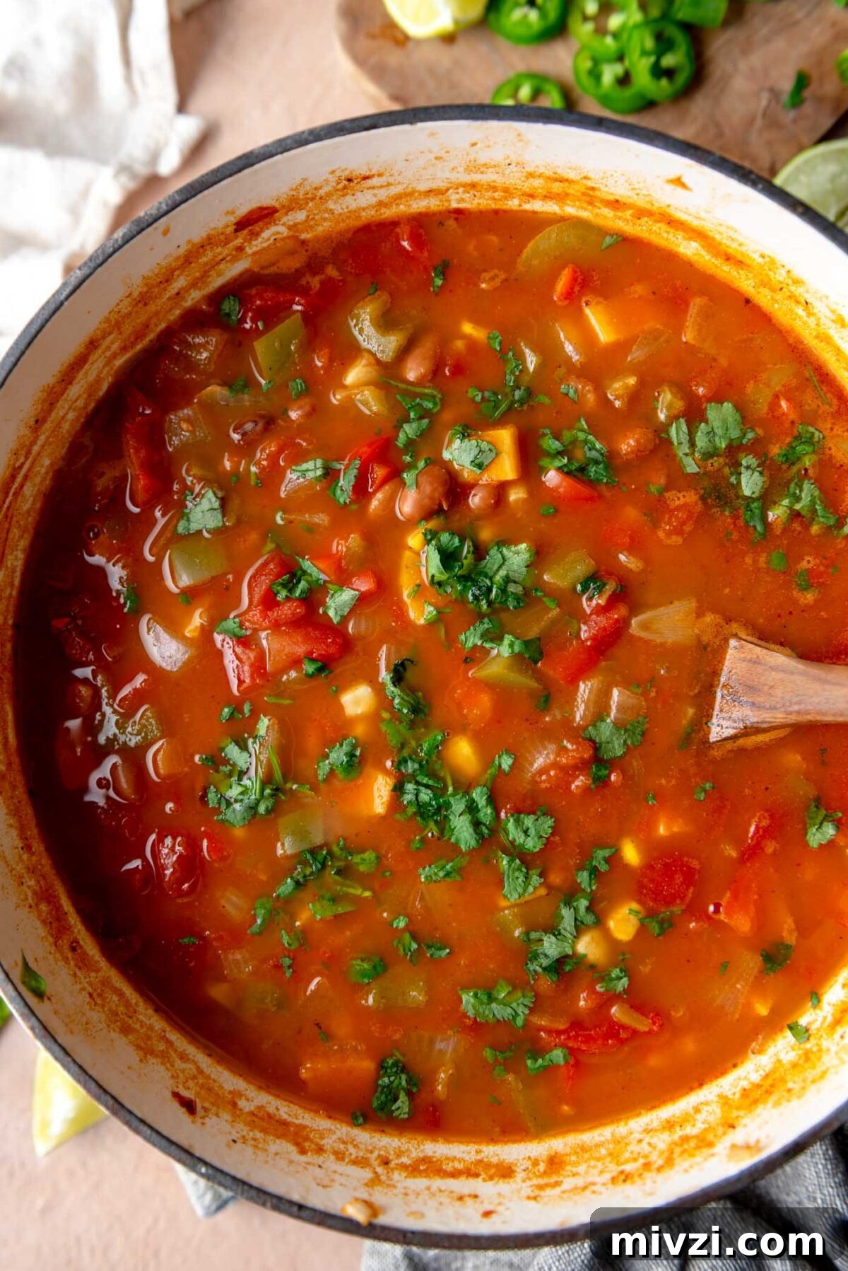 Hearty Vegan Enchilada Soup with Black Beans and Corn 7 Large pot of enchilada soup (tomato-based soup with bell pepper, sweet potato and pinto beans) topped with cilantro in a large pot.