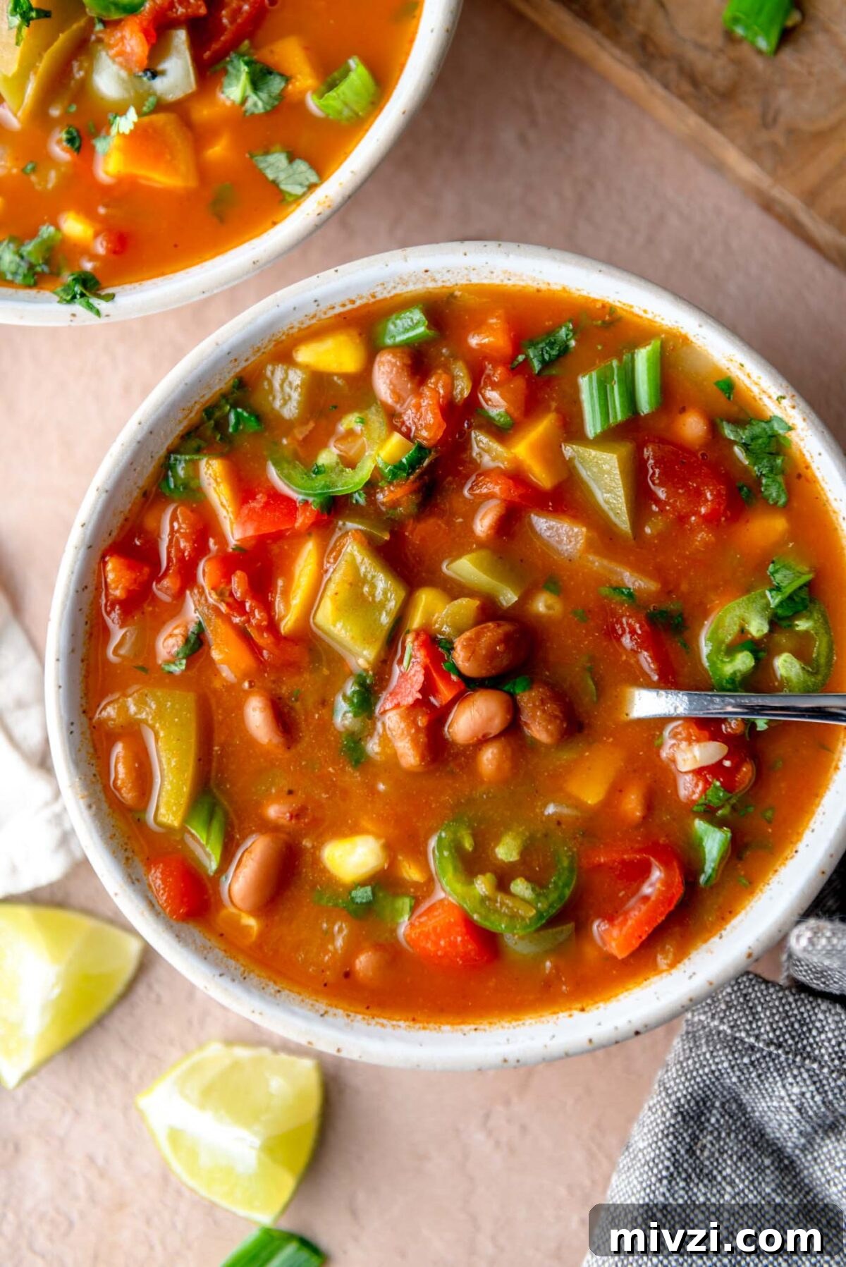 Hearty Vegan Enchilada Soup with Black Beans and Corn 8 Bowl of enchilada soup with bell pepper, sweet potato, onion and cilantro in a tomato-based broth.