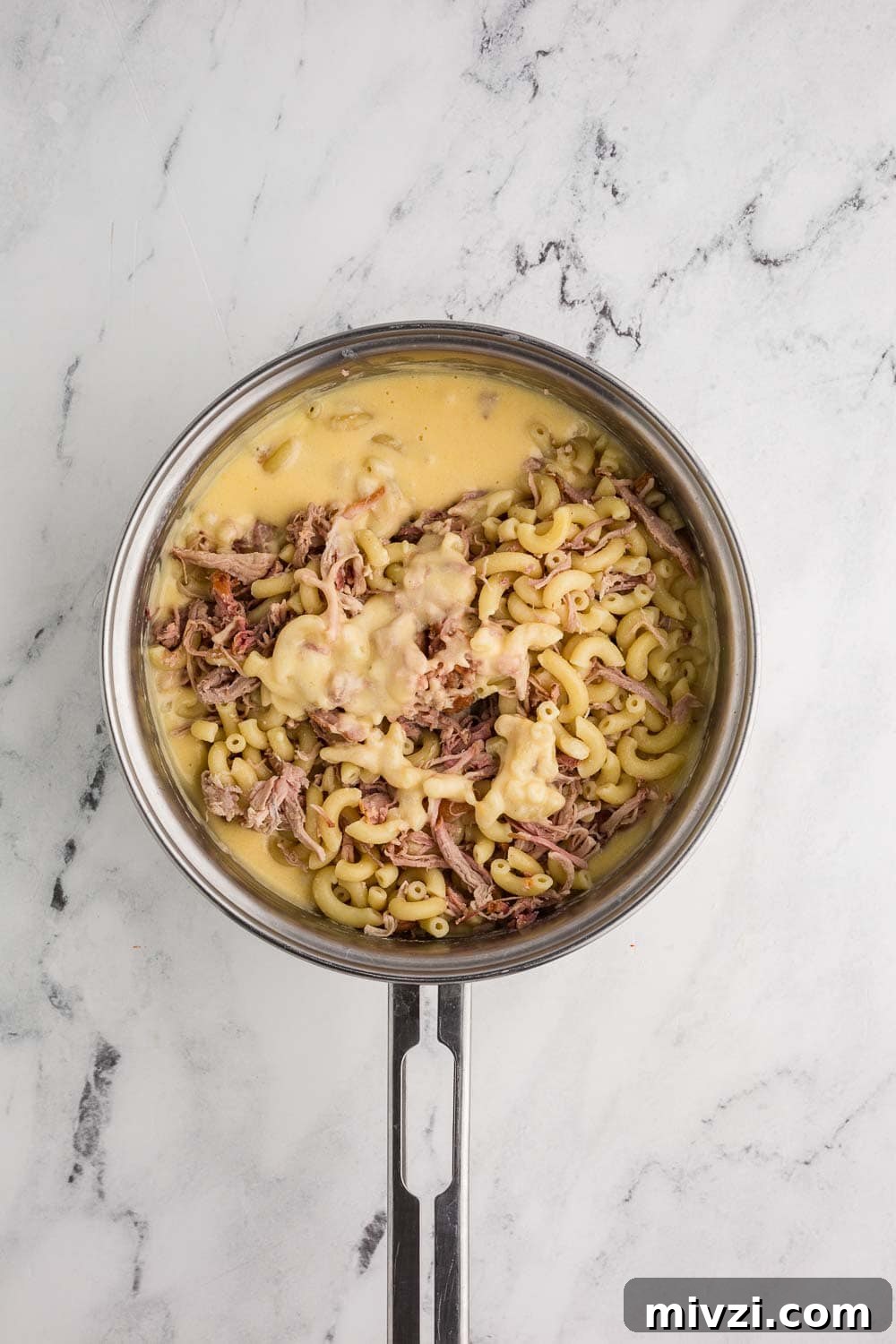 Pulled Pork Mac and Cheese Recipe — Slow-Cooked BBQ Comfort Dish 4 cheese sauce, elbow noodle and pulled pork in a sauce pan ready to mix