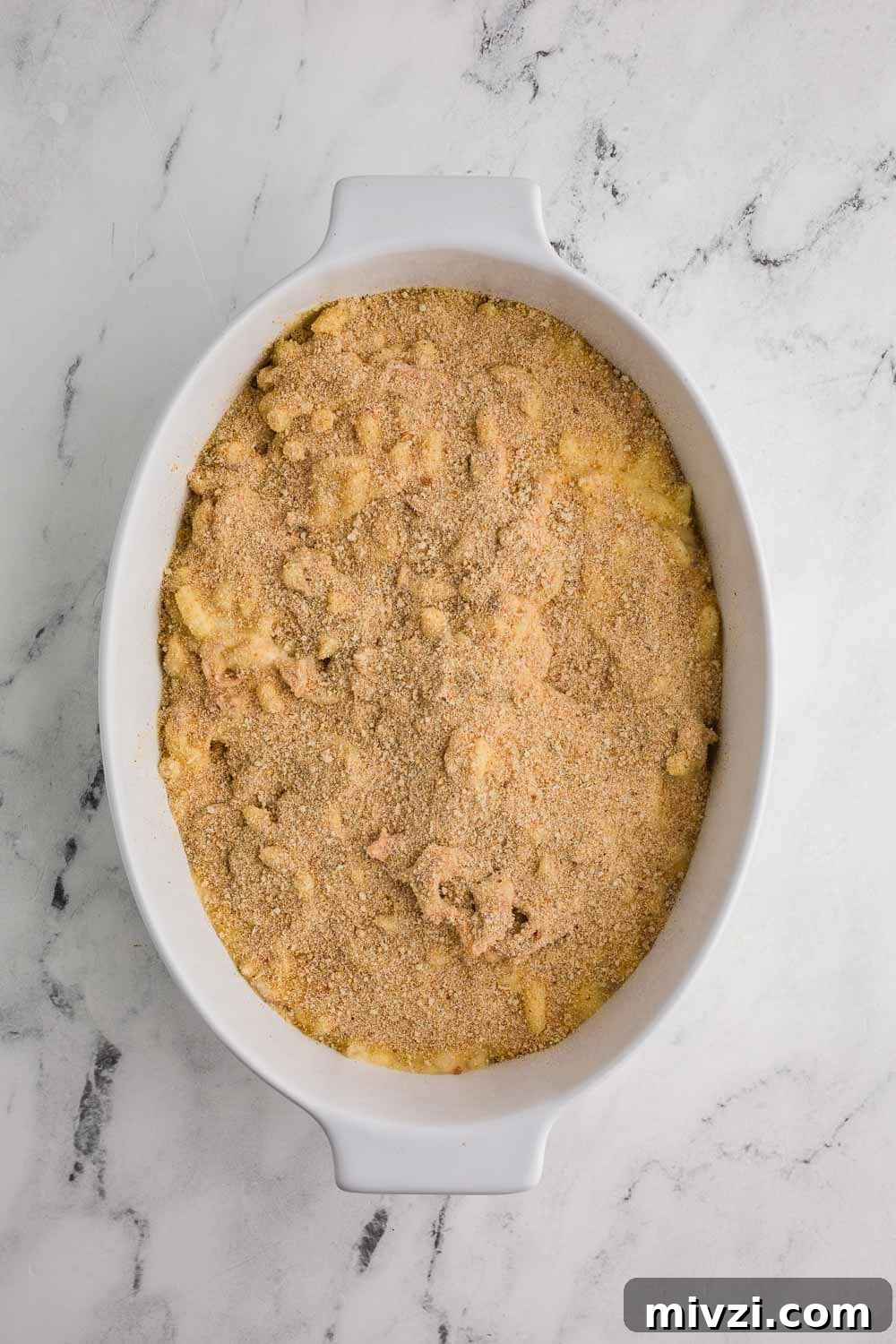Pulled Pork Mac and Cheese Recipe — Slow-Cooked BBQ Comfort Dish 5 oval white casserole dish with Mac and cheese topped with breadcrumbs ready to bake