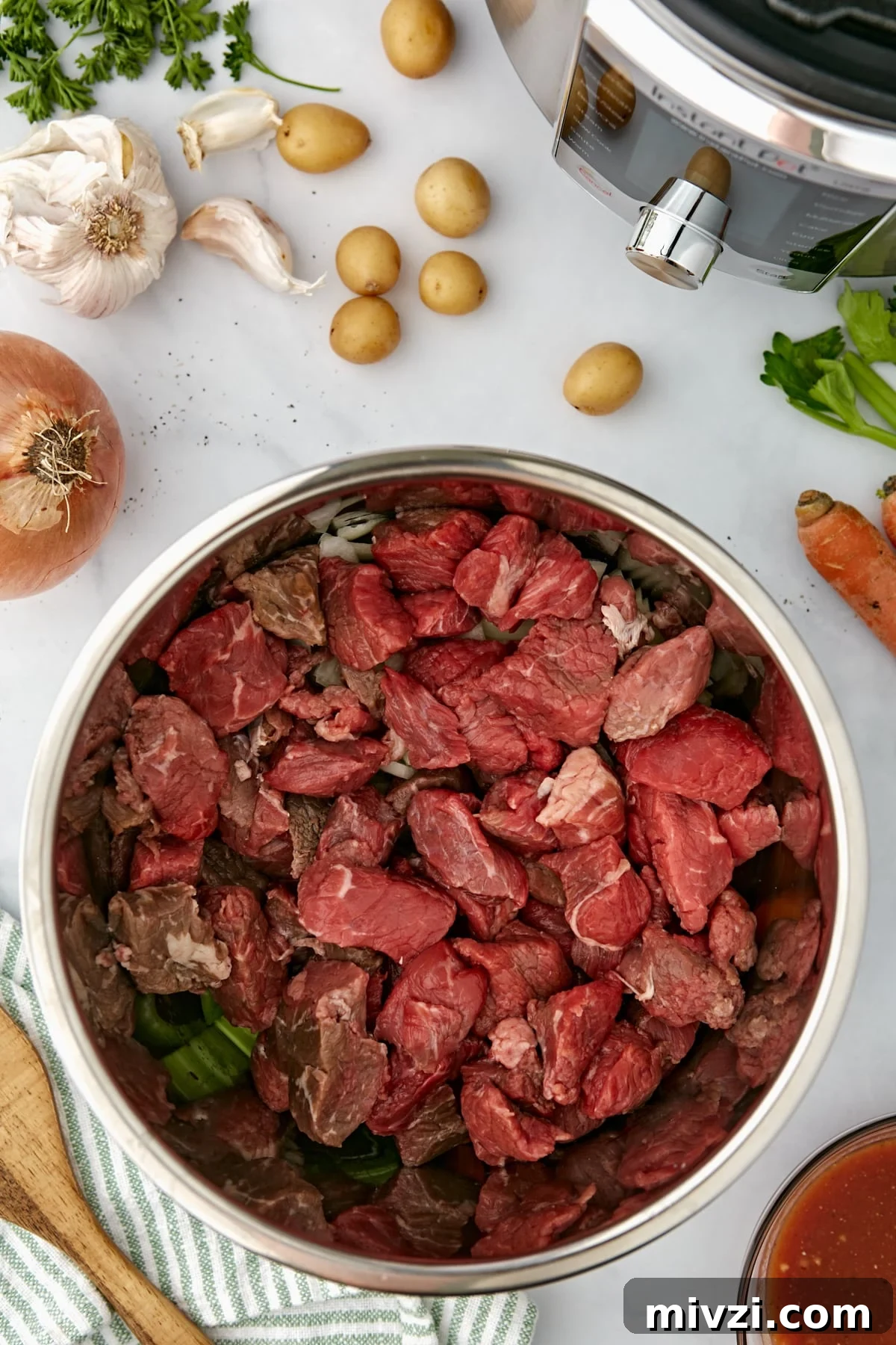 An Instant Pot with beef cubes added to it.