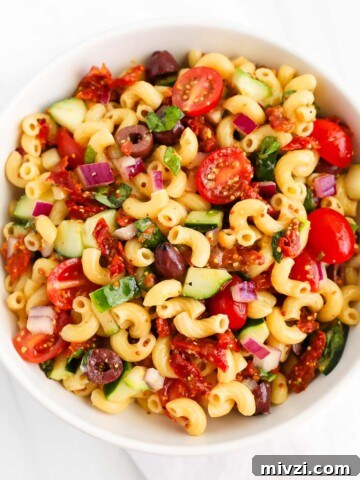 A veggie-filled pasta salad in a white bowl.