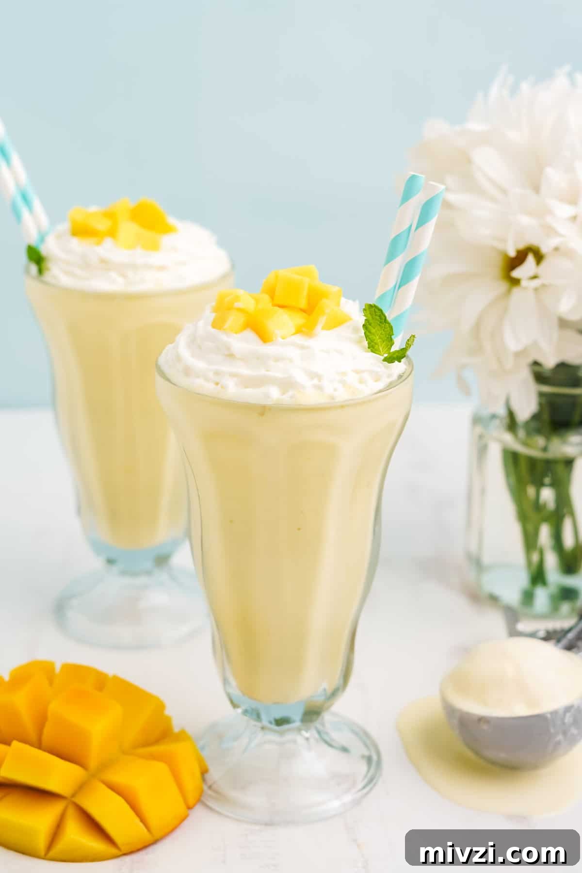 Two old fashioned glasses with mango milkshake.