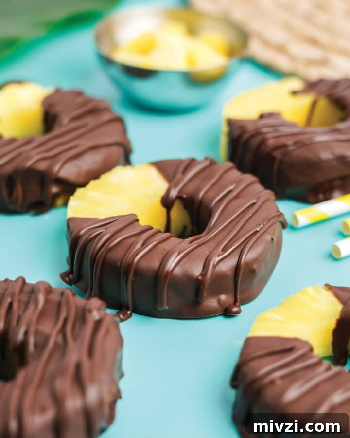 Chocolate covered pineapple on a tabletop with yellow and white straws.
