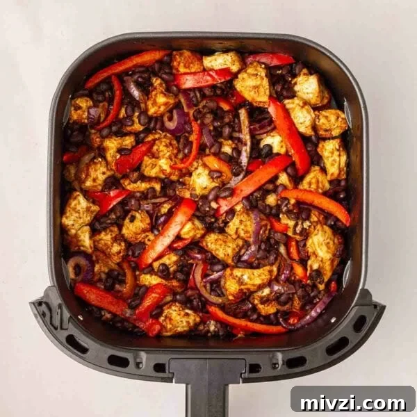 Red peppers, beans, onion and chicken chunks in an air fryer for Air Fryer Mexican Chicken.