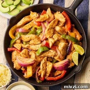 A pan filled with cooked chicken fajitas on a table, with side dishes around, ready to eat.
