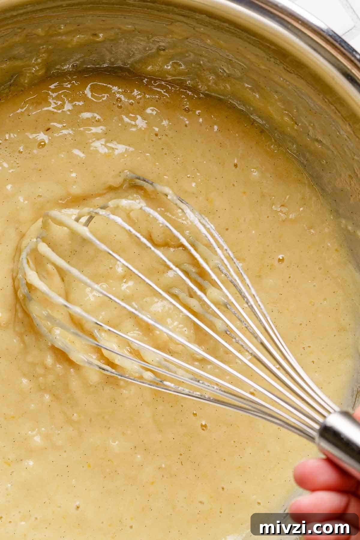 Classic Vanilla Muffins Recipe: Light, Fluffy & Quick 12 completed vanilla muffin batter in bowl with whisk.