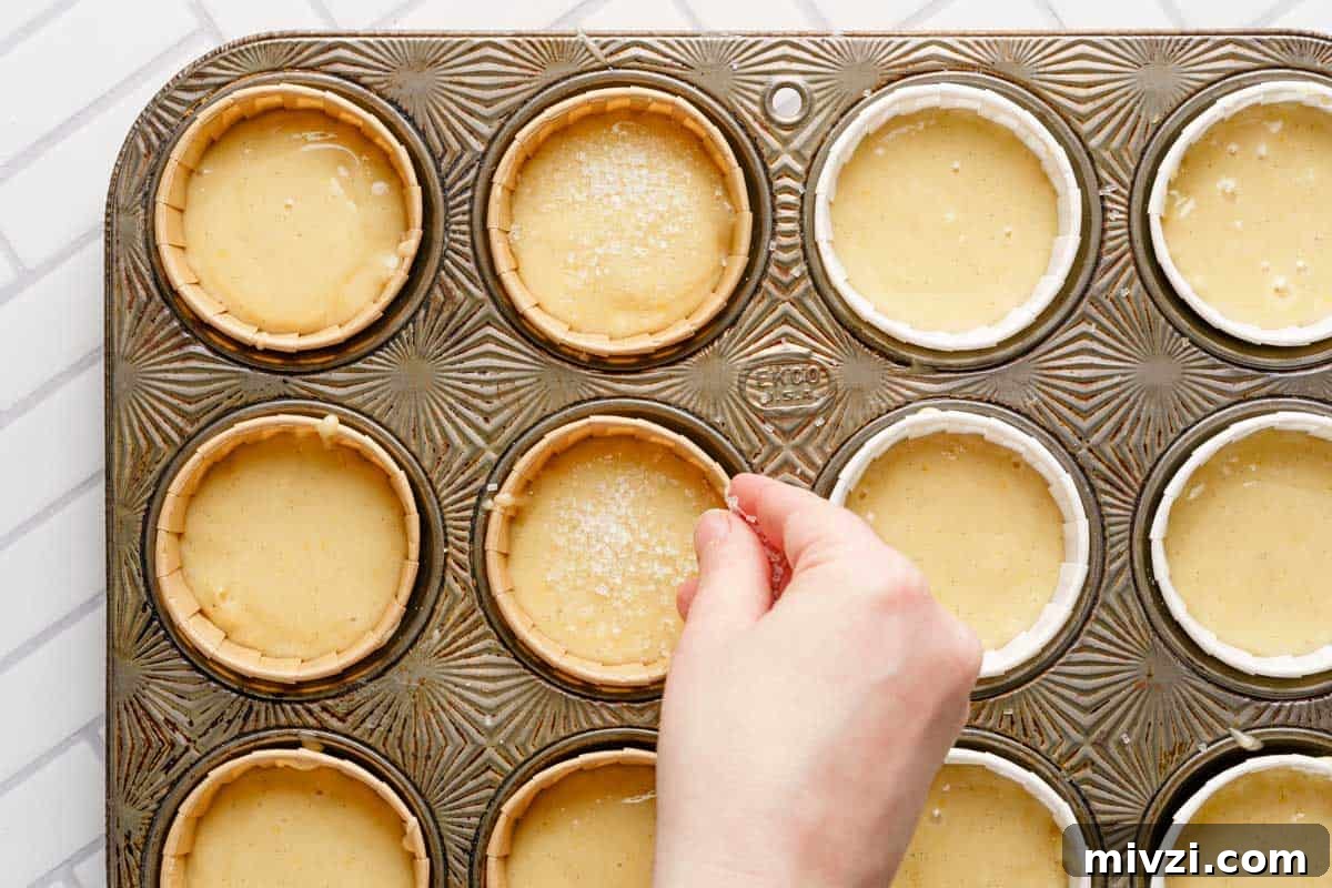 Classic Vanilla Muffins Recipe: Light, Fluffy & Quick 14 hand sprinkling coarse sugar over the top of muffin batter in muffin tin.