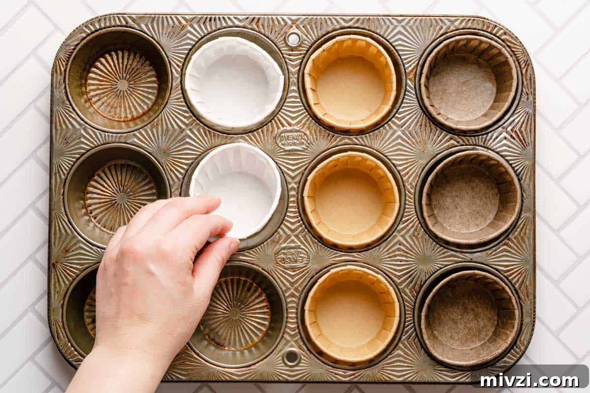 Classic Vanilla Muffins Recipe: Light, Fluffy & Quick 5 hand placing paper muffin liner in muffin tin.