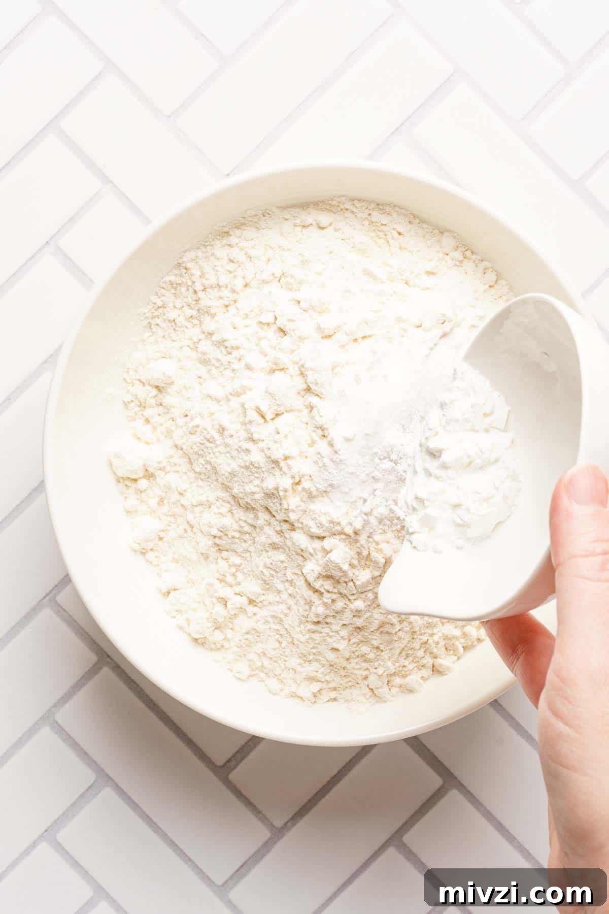 Classic Vanilla Muffins Recipe: Light, Fluffy & Quick 6 small dish of salt and baking powder being added to a bowl of flour.