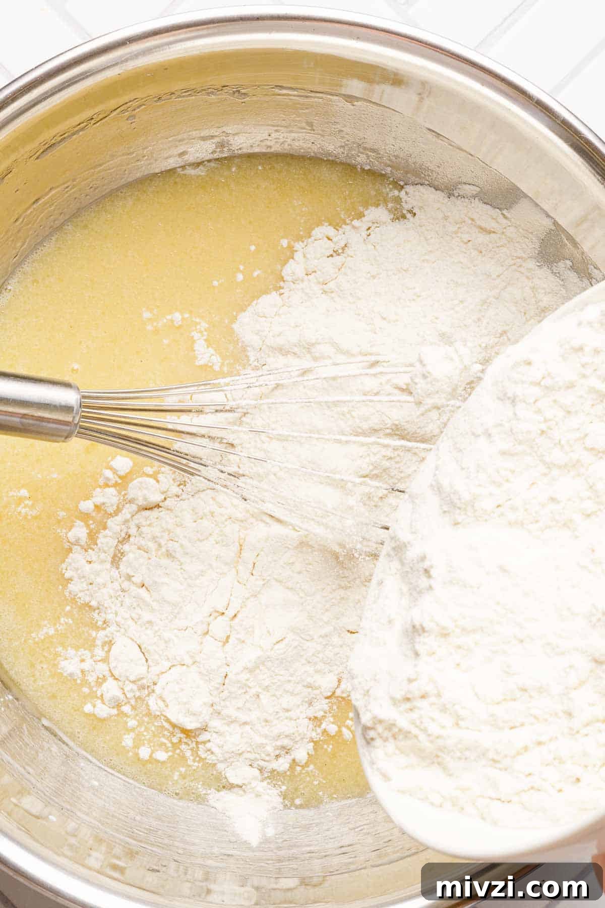 Classic Vanilla Muffins Recipe: Light, Fluffy & Quick 10 flour being poured into bowl with wet muffin ingredients inside.