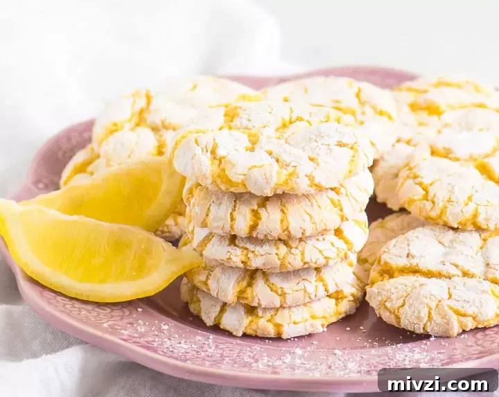 Tangy Lemon Cake Mix Cookies Recipe: Quick Zesty Cookies 4 stack of cookies on a plate next to two lemon wedges