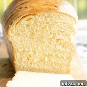 Close-up of a sliced potato bread loaf on a wooden board, highlighting the airy and light crumb structure.