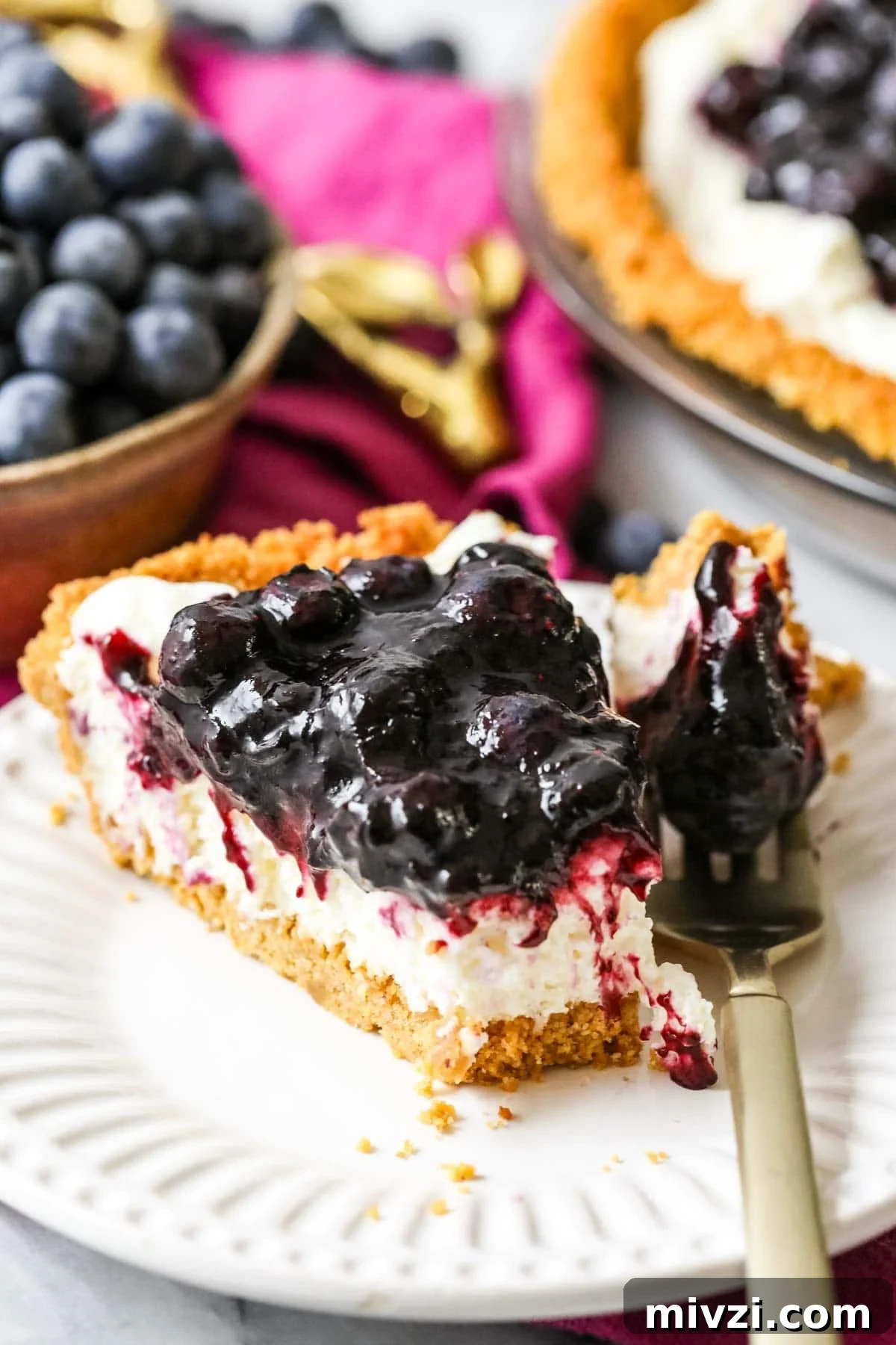 Forkful of blueberry cream cheese pie resting on a plate beside the slices.