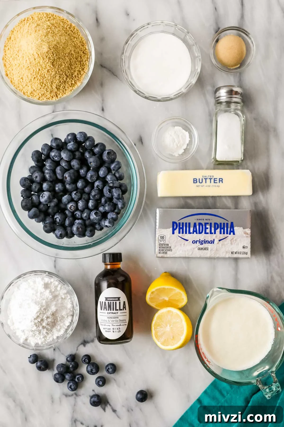 Overhead view of ingredients including graham cracker crumbs, blueberries, cream cheese, and more.