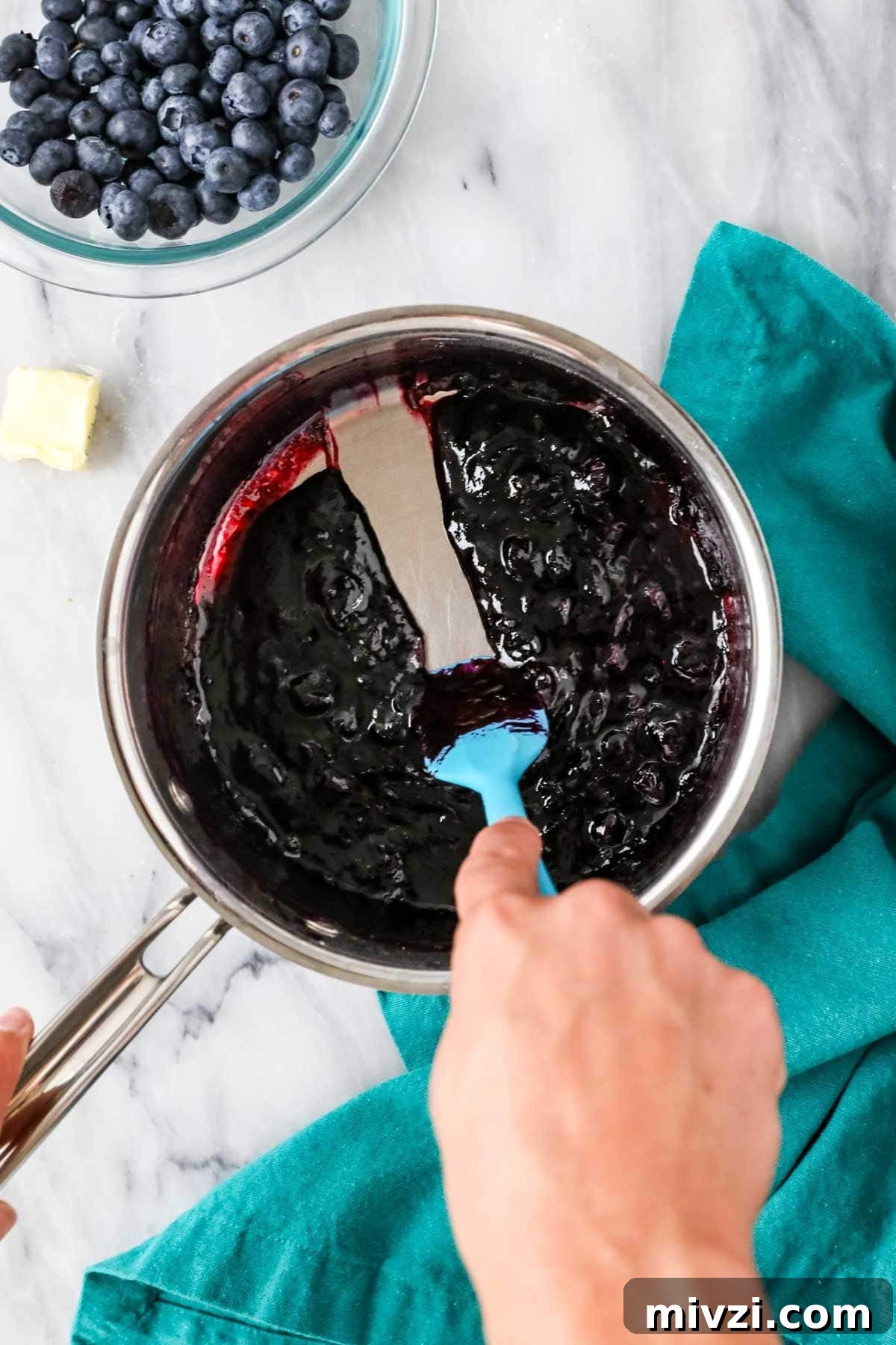 Spatula dragging through a cooked blueberry mixture to show that it has thickened properly.