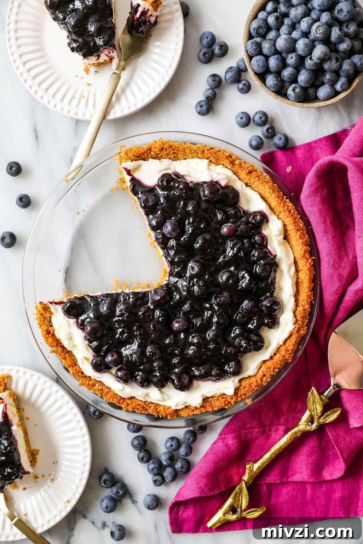 Overhead view of slices missing from a pie made with a cream cheese filling and blueberry topping.