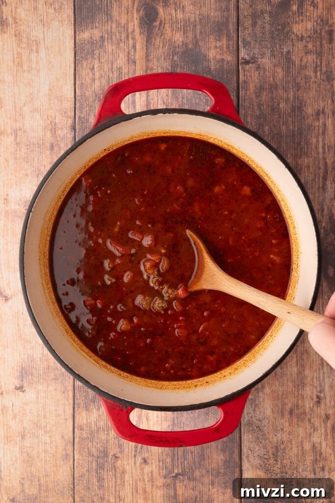 Authentic Texas Chili Recipe for Classic Frito Pie 5 adding tomatoes and liquid to dutch oven for Texas Chili