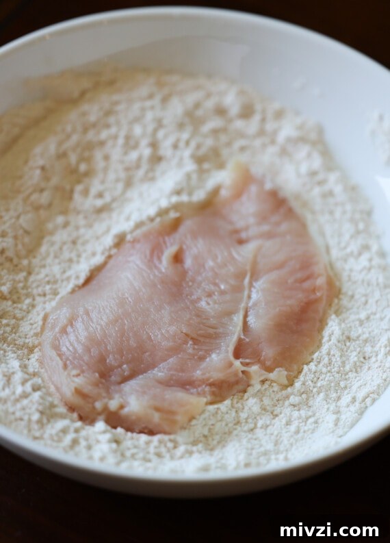 Crispy Pan-Fried Chicken Cutlets with Lemon Garlic Sauce 2 dredging a chicken cutlet in flour