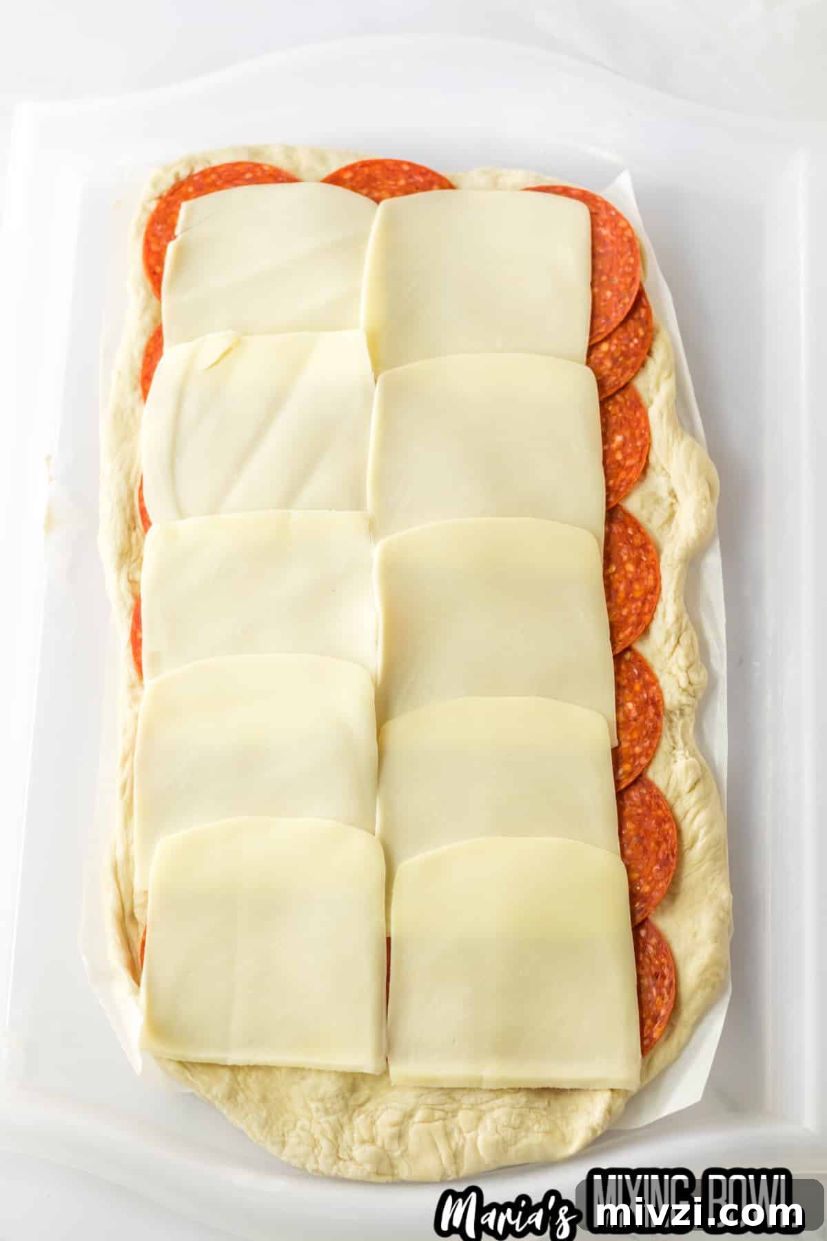 Pepperoni-Stuffed Bread: Cheesy, Savory Pull-Apart Loaf 5 pepperoni slices and mozzarella slices being layered on rolled out raw bread dough.