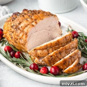 A boneless turkey breast on a white platter with a few slices of meat sliced.