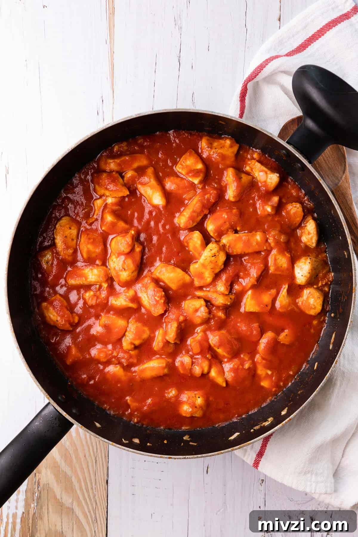 Brazilian-Style Chicken Stroganoff Recipe for Dinner 7 a skillet of chicken pieces cooking in a tomato sauce