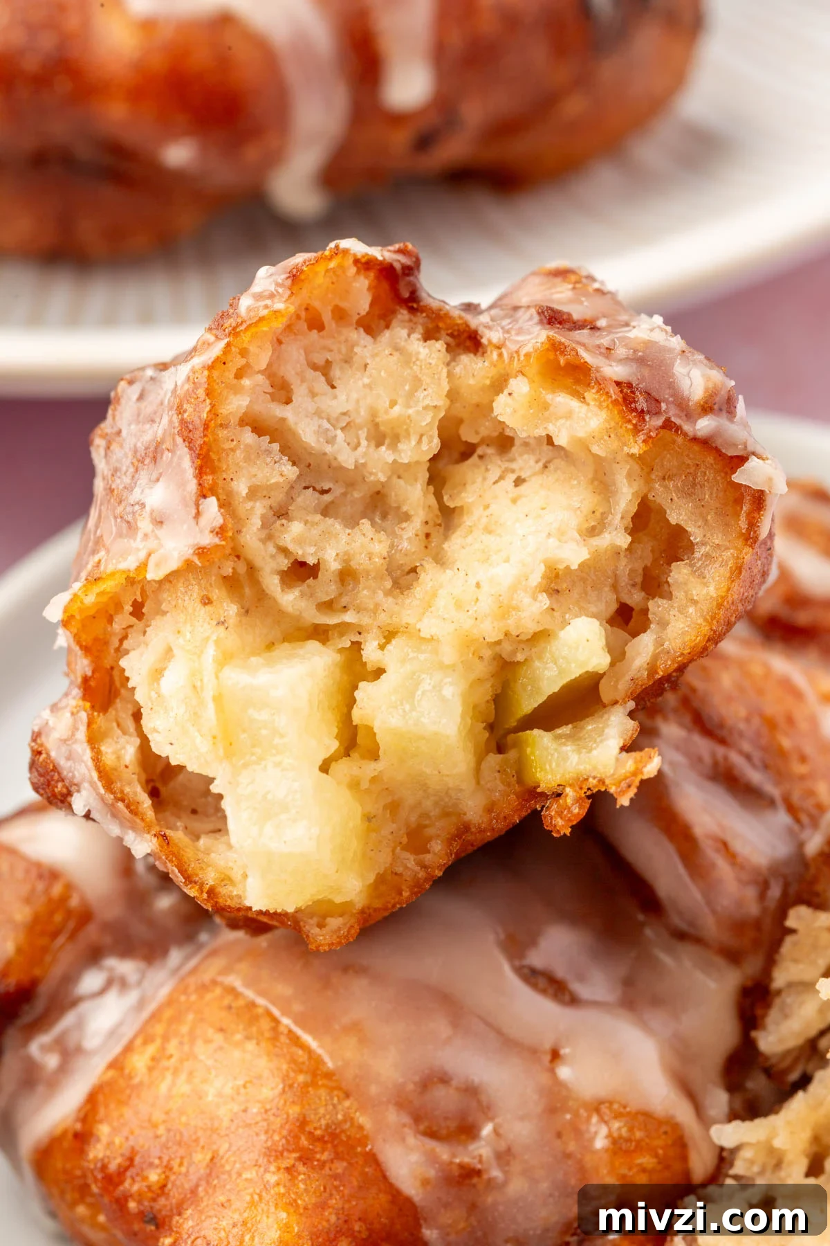Crispy Gluten-Free Apple Fritters Recipe 14 Close-up of a gluten-free apple fritter with a bite taken out, showing a fluffy interior filled with apple chunks and topped with a light glaze.