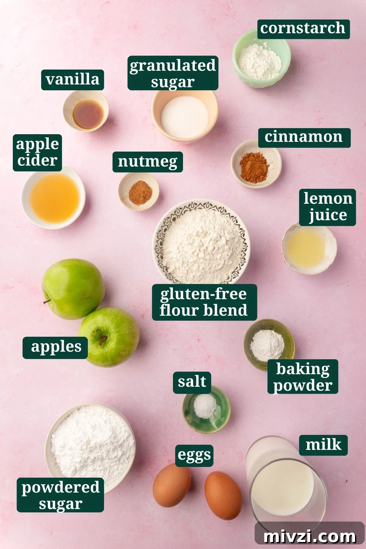 Crispy Gluten-Free Apple Fritters Recipe 3 Overhead shot of gluten-free apple fritter ingredients laid out on a pink surface, including apples, gluten-free flour, sugar, cinnamon, and eggs, each labeled for easy identification.
