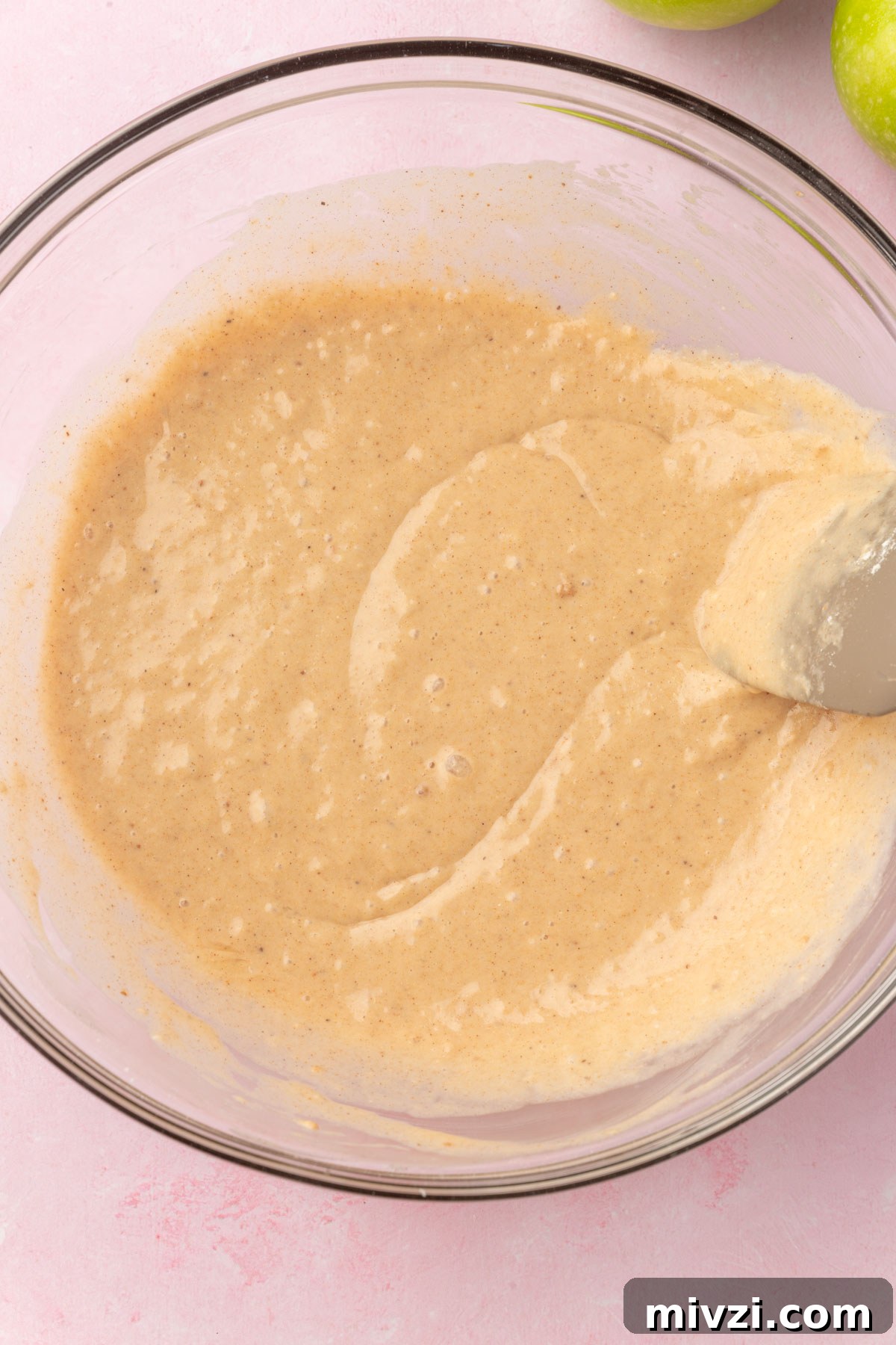 Crispy Gluten-Free Apple Fritters Recipe 8 A glass mixing bowl of apple fritter batter being mixed with a silicone spatula.