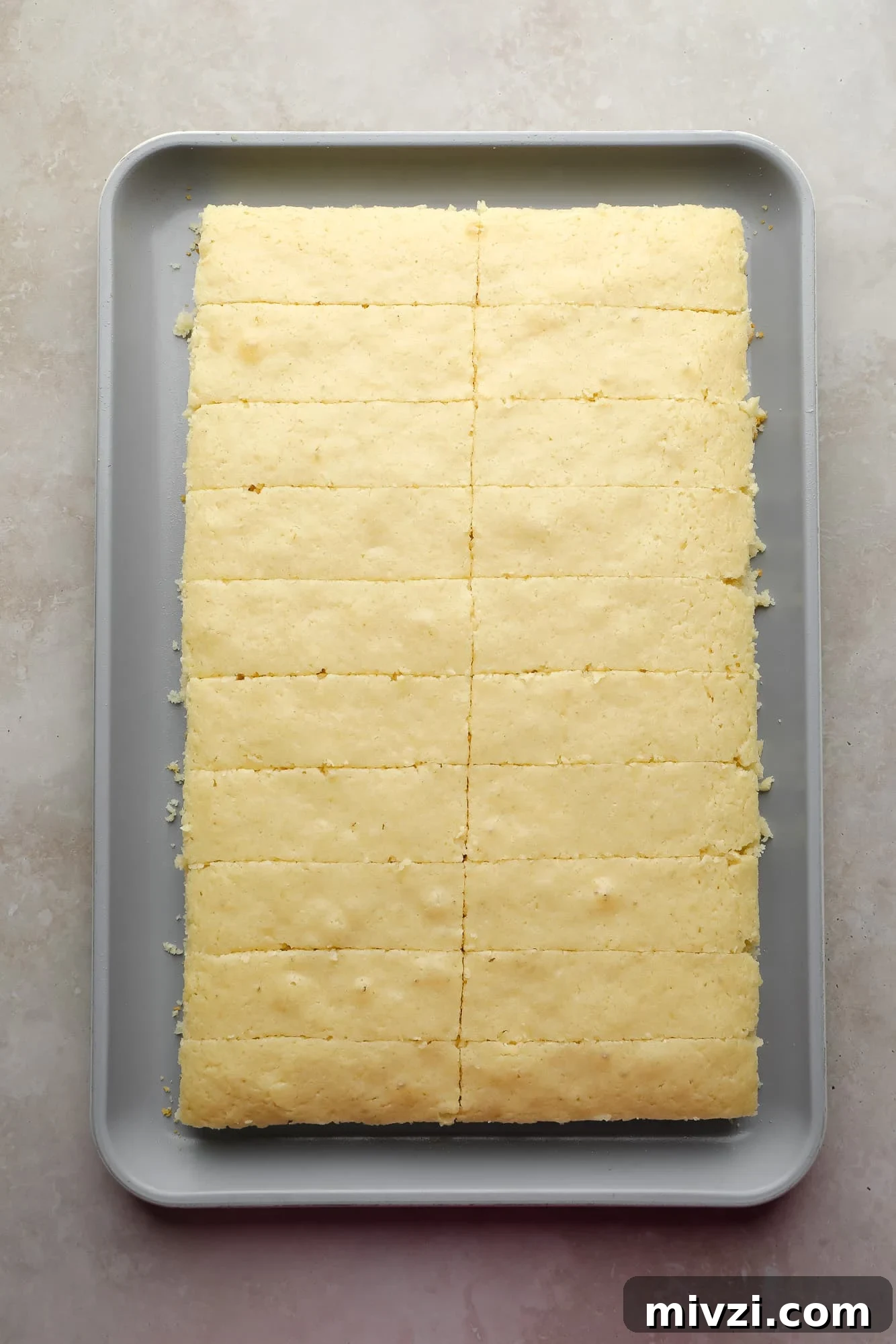 a vegan vanilla cake cut into strips on a sheet pan.