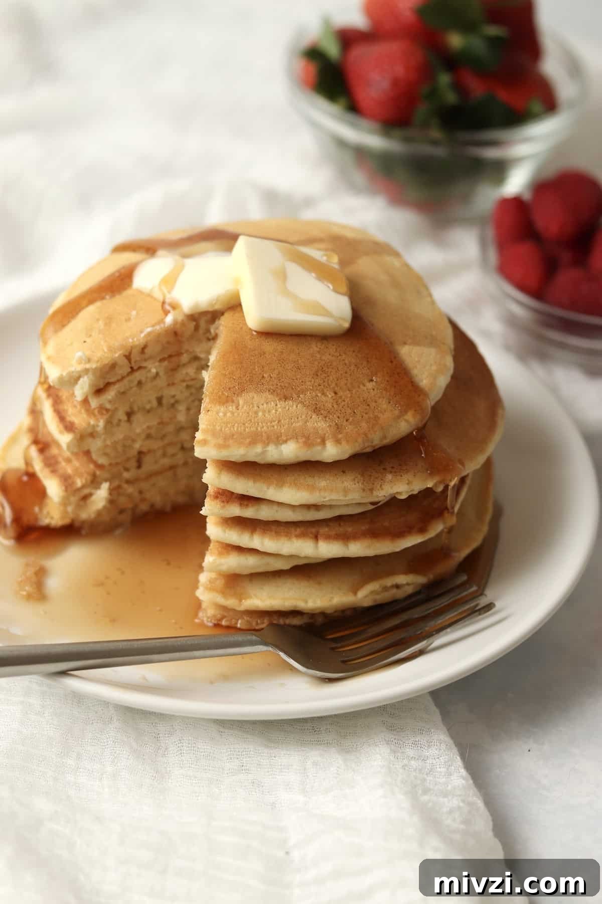 stack of homemade pancakes without milk served with berries and maple syrup