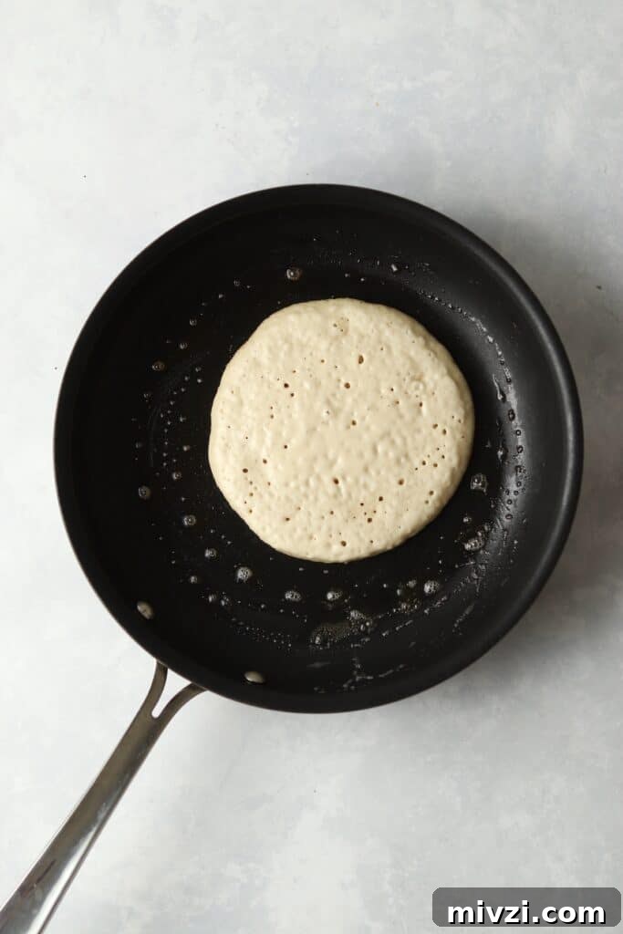 pancake in pan with bubbles on top before flipping